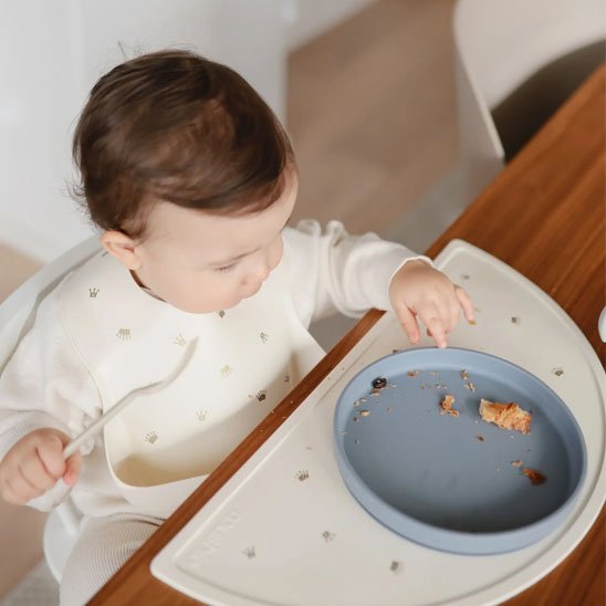 Assiette bebe roundyplate bleu posé sur la table avec garçon
